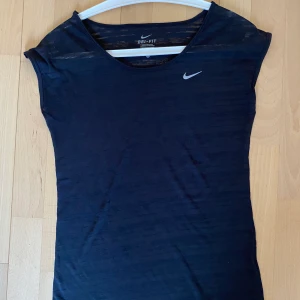 Nike Träningstopp stl XS Svart - Svart träningstopp från Nike. Något genomskinlig med luftigt och tunt material. Storlek XS men upplevs som S :) Endast använd ett fåtal gånger.