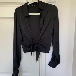 Svart knyt satinblus - En svart knyt satinblus från na-kd i storlek 36. Passar xs/s. Använd ett fåtal gånger, i nyskick. Frakt tillkommer!