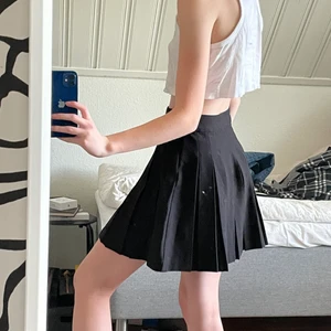 Svart Tennis Kjol - Köptes från New Yorker och säljes pga ej min stil. Använts ganska mycket men är ändå i bra skick. Kjolen har dragkedja och knapp.  20kr + frakt (51kr)  Storlek: XS