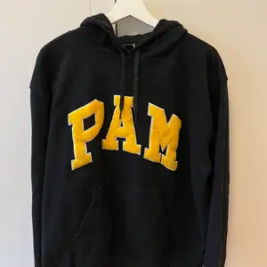 En fin svart PAM ( perks & mini) hoodie med stort gult tryck i storlek L. Hoodien är i bra skick och nypris är ca 1400 kr