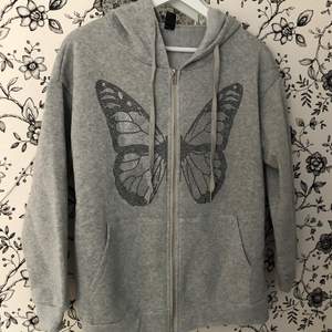Grå hoodie med luva & fint fjäril motiv. Säljer då ärmarna är för korta på mig (är 181). Oanvänd. 