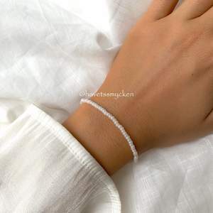 Pärlarmband av skimrande glaspärlor i vit nyans. Perfekt att kombinera med andra smycken! Armbandet är ihopsatt med hållbar elastisk tråd och passar de flesta handleder.