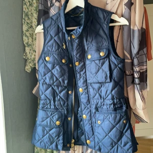 Ralph Lauren Väst  - Nästan helt oanvänd väst från Ralph Lauren! Marinblå med guldiga knappar. Något figursydd. Band i midjan saknas. Storlek XS 