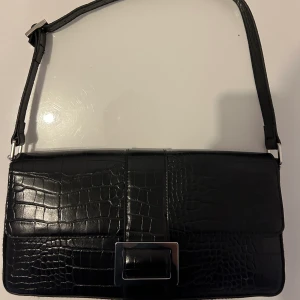 Svart shoulder väska  - Svart axelväska från monki i croc mönster aldrig använd. Köptes för 300 kr prislapp är kvar. 