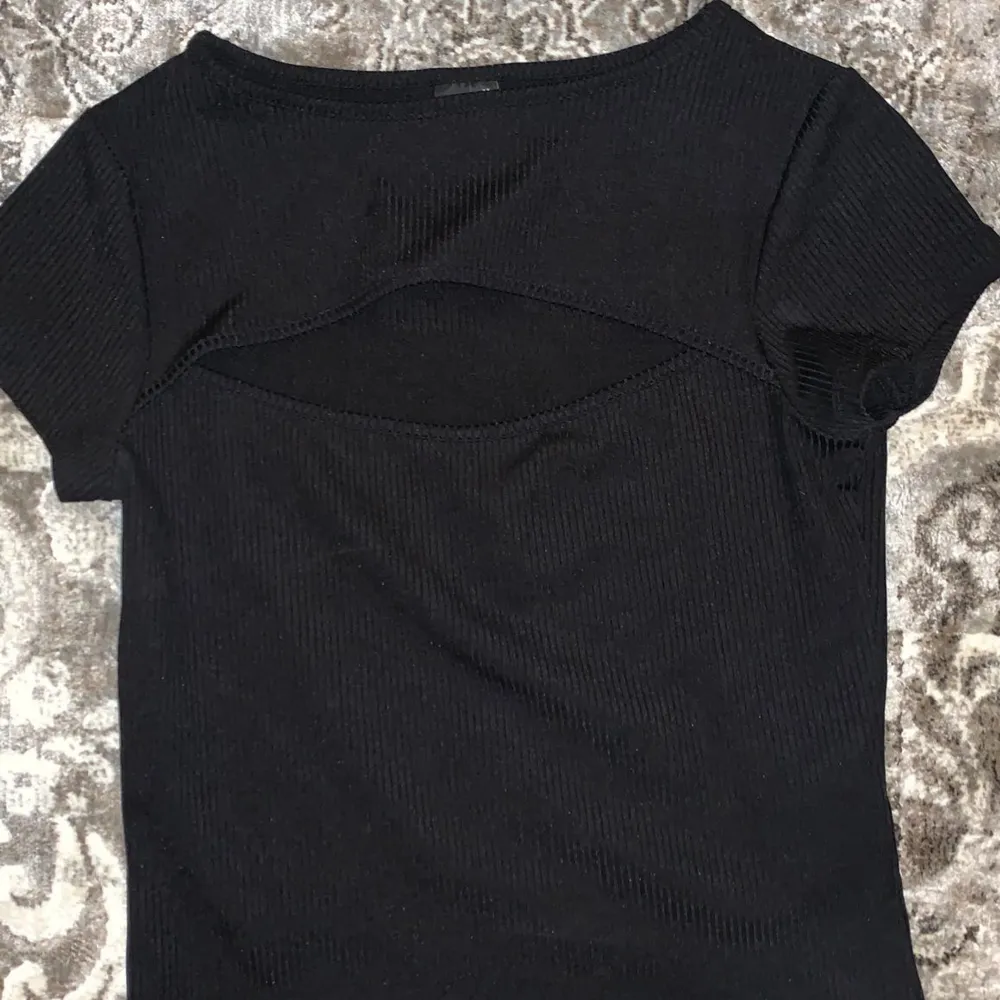 En svart t-shirt som har en liten öppning där fram har använt Max 10gånger . T-shirts.