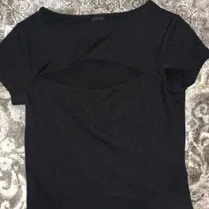 En svart t-shirt som har en liten öppning där fram har använt Max 10gånger 