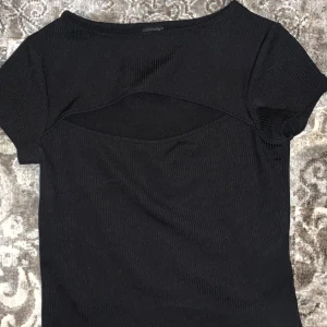 Svart tröja  - En svart t-shirt som har en liten öppning där fram har använt Max 10gånger 