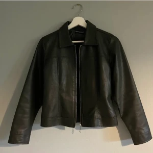 Skinnjacka - Jag säljer denna skinnjacka som jag köpte precis då den inte passar mig i storlek. Alla bilder är tagna av hon jag köpte från. Hon är 160cm så ni får avgöra ifall den skulle passa eller inte. Färgen är en väldigt mörk grön, nästan svart färg. 