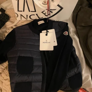 Moncler cardigan  - Mörk blå cardigan köpt i januari 2022 i butik! Altså använd skonsamt i mindre än ett år. Fortfarande mycket bra skick! Köpt för 7000kr💘 Kan även tänka mig byta mot annan moncler cardigan.