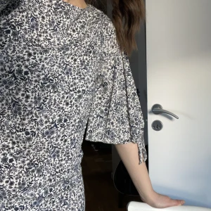 Blommig klänning  - En blommig klänning från H&M. Täcker ca halva låren på mig som är 170. Tunt tyg och ganska sval. Har slitsar hela vägen ner på armarna som försluts med en knut. Du står för frakten!