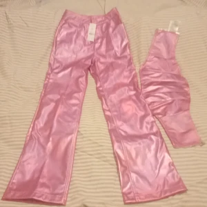 Top och byxa i rosa - Skinn/latex imitation från Gina tricot.. Oanvända med prislapp.. Storlek XS..Butiks pris 800 kr..Jag vill ha 350 för setet... 