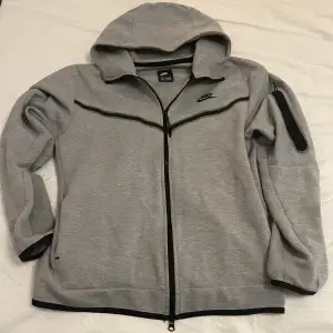 Grå Nike tech fleece hoddie i så gott som oanvänt skick i storlek L men passar även M, tveka inte på att höra av dig om det är något du undrar. Pris kan diskuteras vid snabb affär