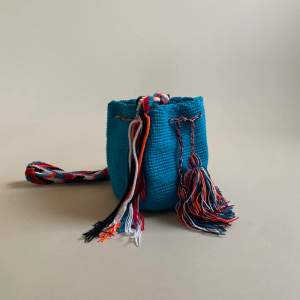 This mini bucket bag is constructed in Colombia with colorful threads made of Cotton and Aloe. The braided shoulder strap can be easily adjusted by tying a knot to shorten. Drawstring Closure with Fringed Pom Poms.
