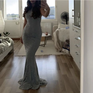 Klänning - Säljer min klänning från Nelly. Den ör grå/blå och helt felfri! Öppen rygg. Kan skicka fler bilder om så önskas💕Jag är 173 och bilden är tagen utan klackar men jag kan ha klackar till utan problem.