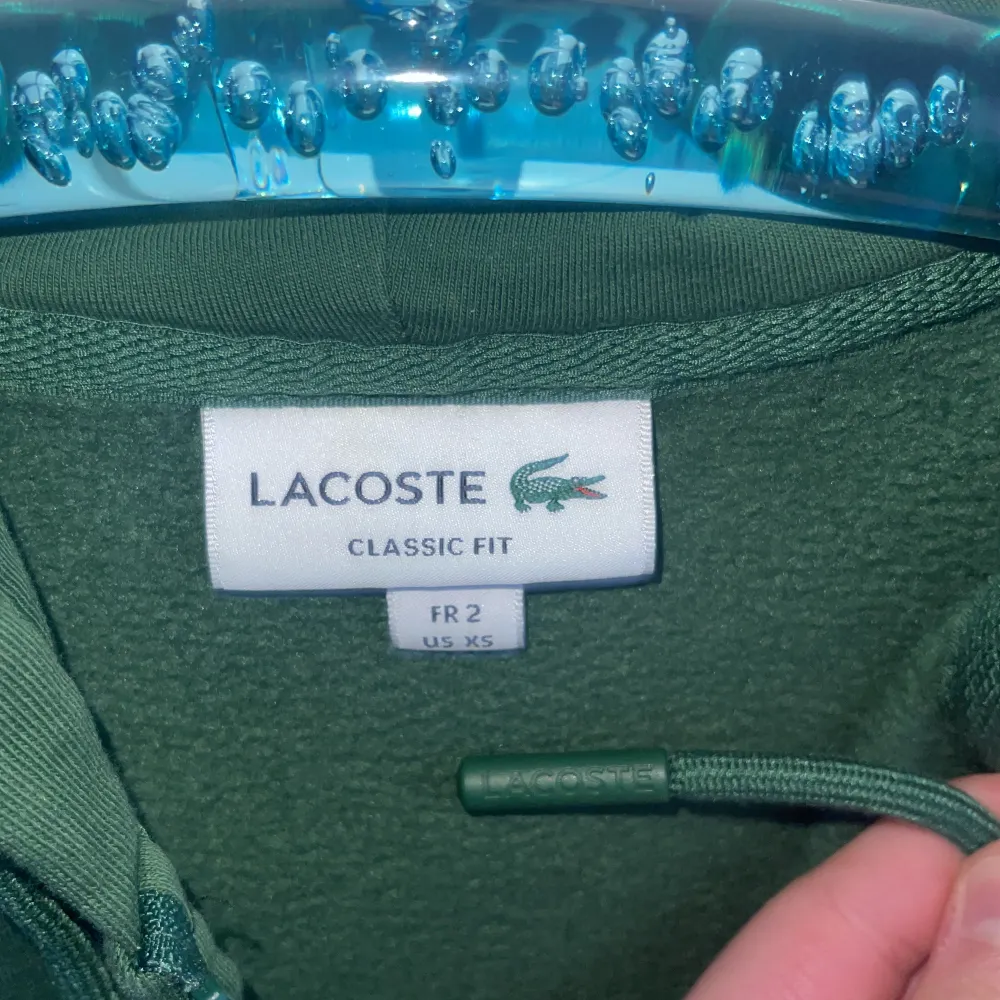 Lacoste hoodie, använd cirka 2 gånger. Grön. Storlek XS, passar 160-170 cm lång. Nypris är cirka 1600 kr, men jag säljer den för 850 kr.. Hoodies.
