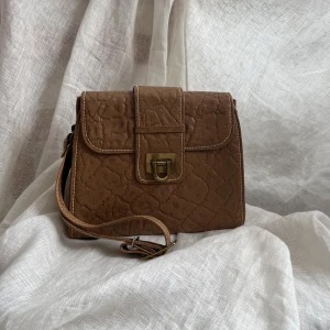 Brun vintage väska - Jättefin vintageväska i brunt läder (?) eller fakeläder. Inte helt hundra på om det är äkta läder eller ej men kan ta reda på det! I fint skick, hel men lite sliten från användning! 🤍 Skickar gärna mått på den! 