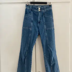 Mörkblå raka/vida jeans med stora fickor i cargo-stil. Väldigt fin dubbelknäppning med snygga knappar. Säljes då de är för korta för mig.