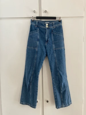 Mörkblå jeans - Mörkblå raka/vida jeans med stora fickor i cargo-stil. Väldigt fin dubbelknäppning med snygga knappar. Säljes då de är för korta för mig.