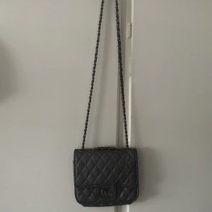 Väska - så snygg & praktisk väska inköpt på Ur&Penn som tyvärr inte kommer till användning 🥰 metallen i spännet har blivit lite missfärgad (se bild 2). färgen är lite grå-silver/metallic, måtten är 17,5x14x5 cm 💕skriv för fler bilder!