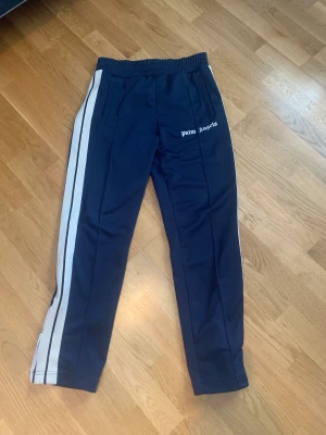 Palm Angels byxor   - WTS Palm angels track pants  Färg: Navy blue  Storlek M  Skick: 8.5/10 ända saken är en tråd som gått upp vid höger ficka men som enkelt kan fixas, se bild  Bud 2.1 Bin 2.5