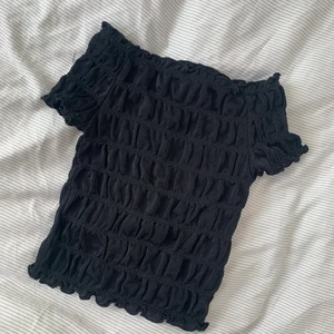 Svart topp - Kortärmad smockad topp som är lite glittrig. Stretchig och otroligt snygg, men för liten på mig. Strl XS