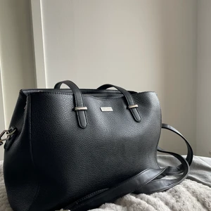 Don Donna väska  - En svart don Donna väska i fint skicka med 3 stora fack och ett litet på baksidan, en lång axelrem medföljer. lite slitningar på dem små remmarna.   250 ink frakt 💕 eller mötas upp  