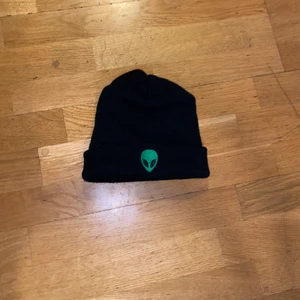 Svart Mössa/Beanie med Alien Motiv - Bra skick, sällan använd. Lite Större Beanie karaktär. Perfekt streetwear/skatemössa. 