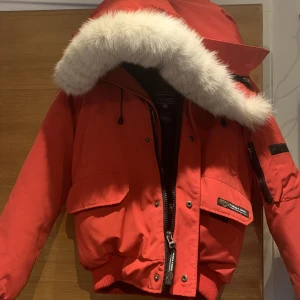Canada Goose Jacka - Röd Canada Goose jacka med äkta päls. Tjock och varm, perfekt jacka nu till vintern. Väldigt fint skick, inga synliga slitningar. Vid frågor tveka inte på att höra av dig. Pris går att diskutera, vill bli av med den! ❤️‍🩹(kan hämtas eller mötas upp)