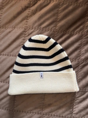 NN07 Mössa - Vit/Blå randig mössa i 100% merinoull från NN07. Endast använd 1-2 gånger! Samma stil som på hemsidan men annan färg såklart