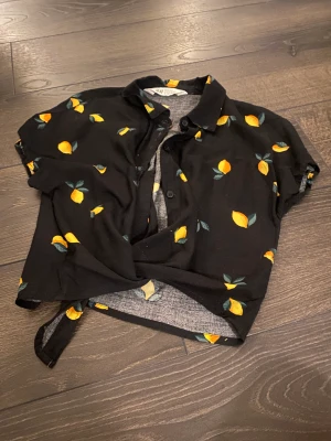 Blus - En svart blus med gula citroner och knytmidja
