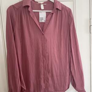Rosa randig skjorta från HM i tunt material perfekt till sommaren. Aldrig använd, prislapp finns kvar. I strl 34 men passar även som en 36. 