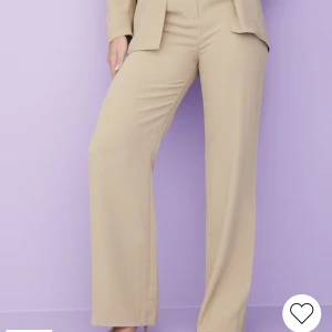 Beigea kostymbyxor - Ett par beigea kostymbyxor från Nelly i storlek 42. Aldrig använda, endast provade, alla lappar sitter kvar