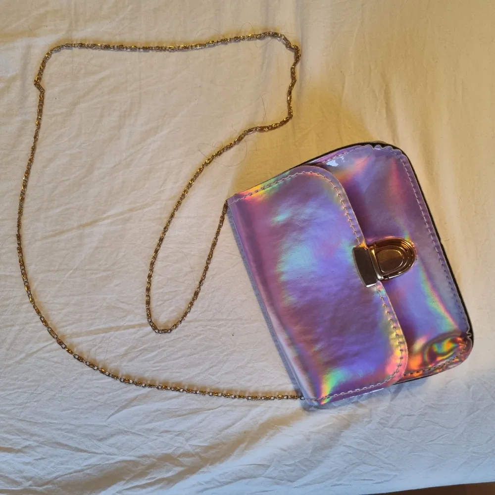 Rosa/lila/holografisk handväska med guldfärgat spänne och kedja. Med fake-läder på insidan. Köpt på Shein, endast använd någon enstaka gång.. Väskor.