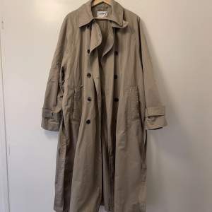 Beige trenchcoat från weekday i storlek S. Modellen på jackar heter ”travis oversized trenchcoat”. Använd 2 gånger, skicket är som nytt! Jackan är ljusare än vad den ser ut på min bilder. Nypris 1400 kr.