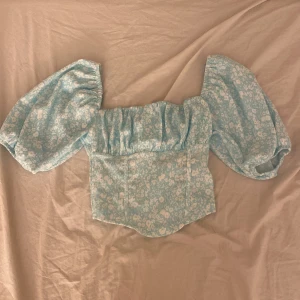 Puffärmad topp - Gullig blå puffärmar topp med blommönster. Endast använd 1 gång. 