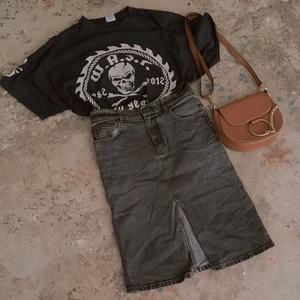 Svart jeanskjol, stl 38  - Grå/svart jeanskjol med hög midja som slutar precis ovanför knäet med slits fram. Har 4 stycken fickor (två fram, två bak). Gjord i 98% bomull och 2% elestan. Jeanstyget har stretch i sig och med det följsamt över både stuss och midja.  Är i fint skick