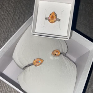 Caroline Svedbom smycken - Armband och ring från Caroline Svedbom. Stenen är i orange/aprikos färg. Varken armbandet eller ringen är använd.  Nypris armband: 695kr Nypris ring: 495kr