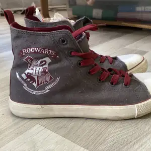 Ett par skor med Hogwarts märke och text på. Strl 42. Använts ett fåtal gånger. Behöver en tvätt.