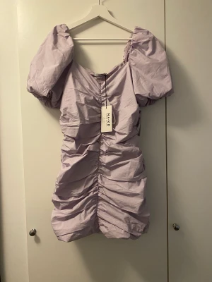 Klänning från NAKD - Oanvänd klänning från Nakd i storlek 38. Färgen är ljuslila. Nypris 399 kr