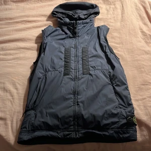 Stone island vest blå - Denna Stone island vest har endast använts ett par gånger. Vesten har två varianter en med huva och en utan (se bilderna). Vesten har inga som helst skador. Kan diskutera pris vid snabb affär. 