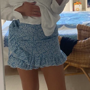 Söt ljusblå kjol - Söt ljusblå minikjol med volang och knyte i sidan! Storlek S men skulle säga att den även passar M🥰 Kjolen har oxå en dragkedja i bak!