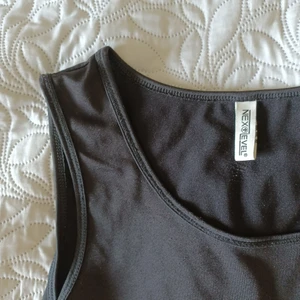 Långt svart linne - Långt svart linne i glansigt material. På lappen står det att storleken är XL/176, jag skulle säga att storleken är S eller M. ~ Varan kostar 50kr och frakten kostar 39kr