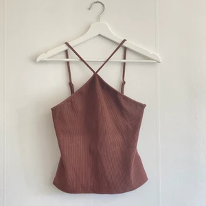 Brun topp - Jättefin ribbad top med korsade snören fram. Använd ett fåtal gånger därav i fint skick men sömmarna har spruckit lite på ena sidan (se bild 3) men det är inget som syns då det sitter under armen. Strl S. Skriv för fler bilder!