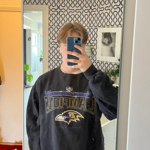 American football sweatshirt Ravens - En vintage, svart, amerikansk fotbolls sweatshirt köpt på second hand. Tröjan är i bra skick bortsätt från lite sprucken text men det märks knappt. Skriv för fler bilder eller funderingar kring tröjan:)