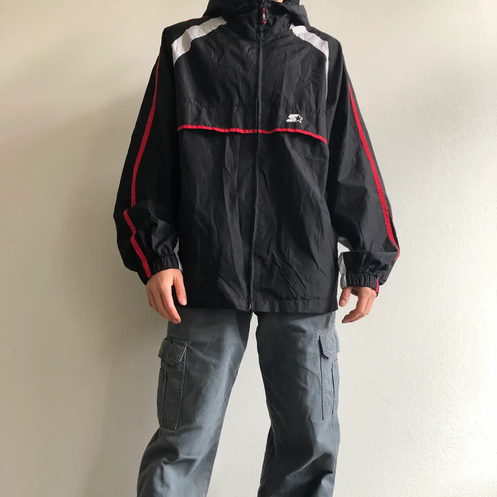 Black shell jacket with hood with red and light grey parts. It’s in very good condition, I bought it second hand myself and barely used it, hopefully it finds a new owner that has more use for it :). Jackor.