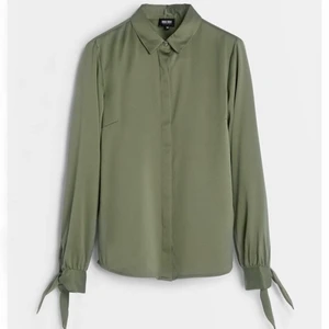 Olivgrön blus med knyten - 🫒Olivgrön blus i skjortmodell med knyten vid ärmslut. Från bubbleroom i storlek 38. Dold knäppning hela vägen ned. Hittade en lite tråddragning framtill på höger sida, bild kan skickas. SKICKAS med postnords fraktpåse för 63kr, önskas spårbart går det 