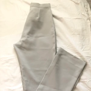 Ljusgråa byxor - Secondhand ljusgråa byxor. Tajta från höfterna till knäna och vida från knäna och ner. Materialet är tunt. Bra skick. Skriv om ni har frågor!