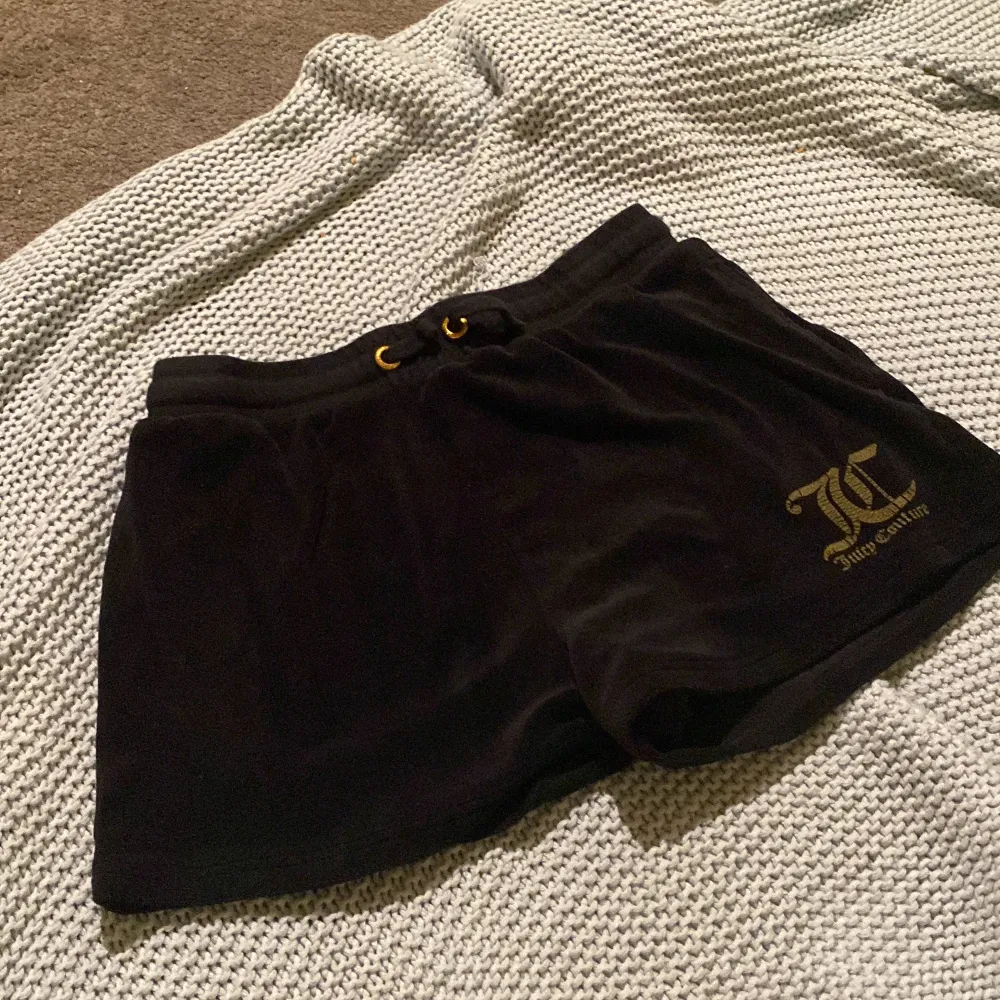 Svarta juicy couture shorts i storlek 14/15 ålder. En ficka på baksidan, shortsen är använda och logan är sliten pågrund av tvättmaskin. Originalpris 500kr. Shorts.