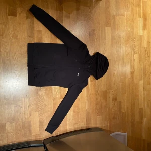 Svart hoodie - En svart hoodie med dragkedja från Puma. Ett litet tryck på högersida. Storlek xs. Väldigt fint skick! Använd endast fåtal gånger. Pris: 180 kr   Frakt: 49kr