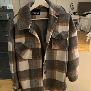 Jacka - Rutig kort kappa i gott skick. Sömmen inne i armen har dock spruckit (se bild), men utanpå är jackan i mycket gott skick då den inte är använd så många gånger  Nypris 849kr 